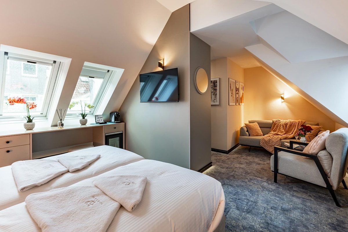 Ein Schlafzimmer mit einem Bett, einem Schreibtisch, einem Sessel, einem Fernseher und einem Sofa.