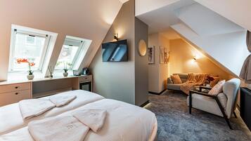 A bedroom with a bed, a desk, a chair, a TV, and a sofa.