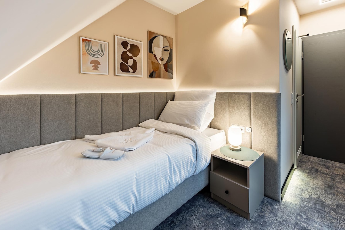 Ein modernes Schlafzimmer mit Bett, Nachttisch und Kunstwerk an der Wand.