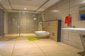 A modern bathroom with a glass shower enclosure, a white sink, and a mirror above it. - Niraamaya Retreats Vaidekam Kannur (Talipparamba)