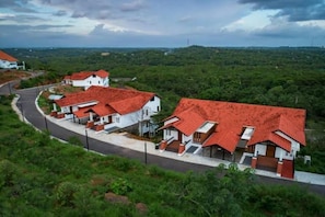 A residential area with houses having red roofs, surrounded by greenery. - Niraamaya Retreats Vaidekam Kannur (Talipparamba)