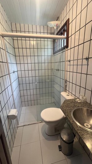 A small bathroom with a shower, toilet, and sink. - Orla Náutica (Barreirinhas)