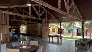 Área externa coberta com mesa de pingue-pongue, cadeiras e mesa de jantar com um vaso de flores.