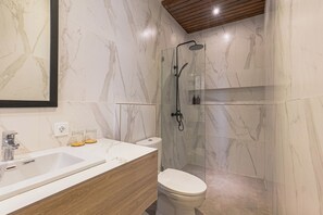 Een moderne badkamer met een marmeren wastafel, houten opbergmeubel, een douche met glazen wanden en een toilet.