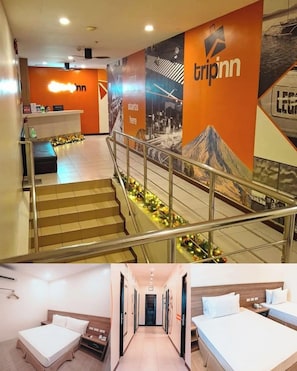 A hotel lobby with a reception desk, a staircase with railings, and a mural with the hotel name. - Trip Inn by Zuzu (Legazpi)