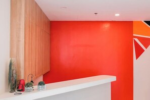 Una recepción con un mostrador blanco y una pared roja al fondo.
