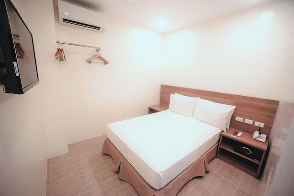 A hotel room with a bed, bedside table, and a mirror. - Trip Inn by Zuzu (Legazpi)