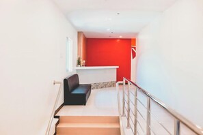 Un escalier avec un banc noir, un mur rouge et un plafond blanc.