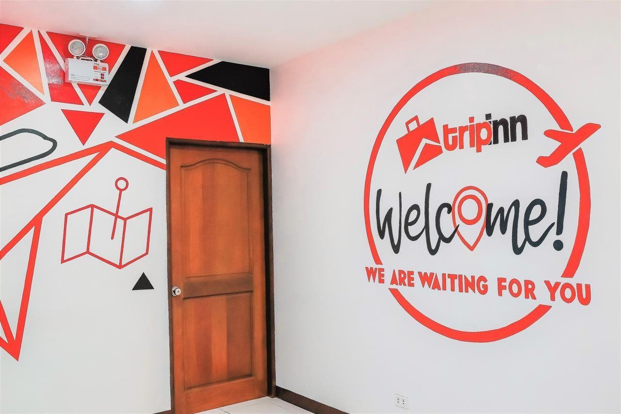 A wall with a 'Tripinn Welcome!' sign and a geometric design.