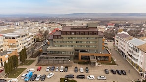 A multi-story hotel with a parking lot in front, surrounded by other buildings.