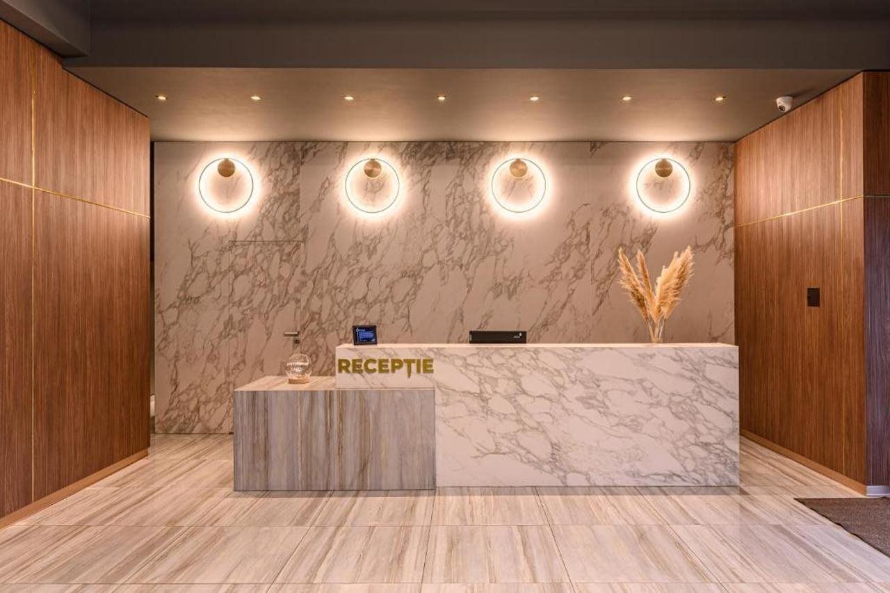 A reception desk with a marble countertop, wooden paneling, and circular wall sconces.
