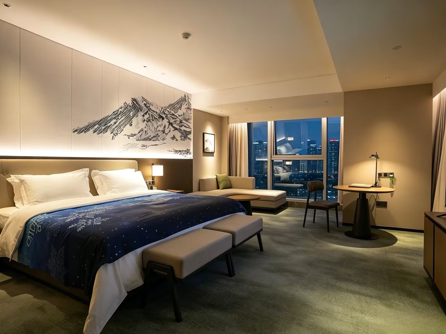 A hotel room with a large bed, a desk, a chair, and a view of the cityscape.