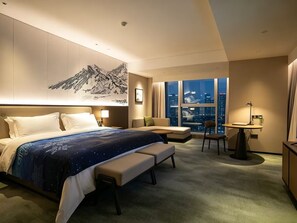 A hotel room with a large bed, a desk, a chair, and a view of the cityscape. - Runda Grand Skylight International Hotel Pingxiang (Pingxiang)