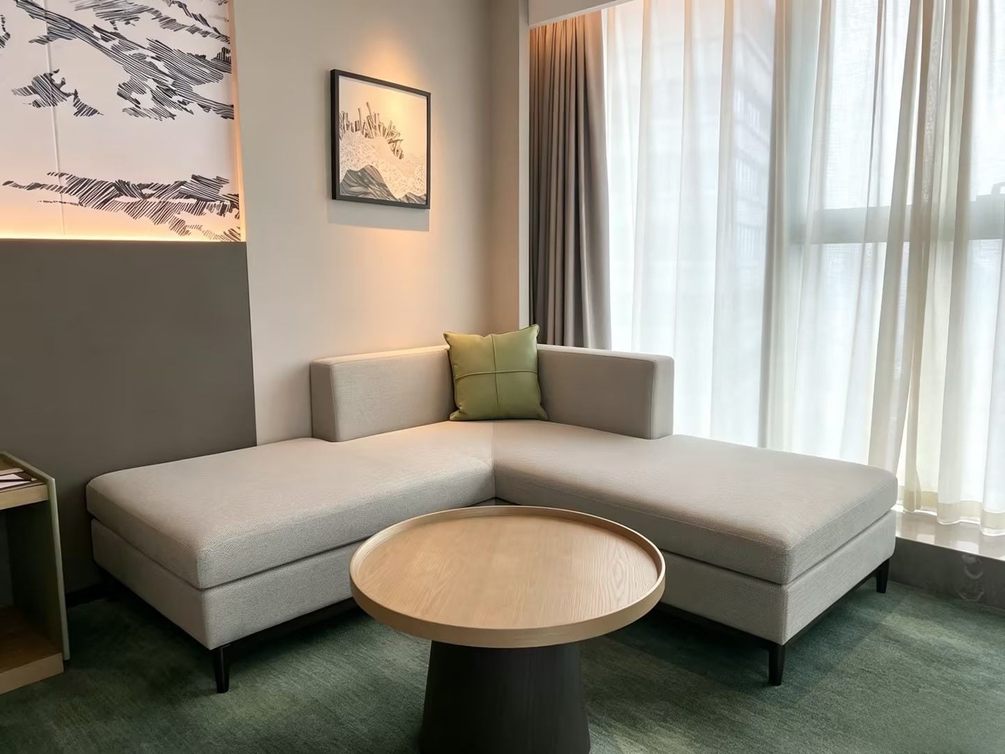Una sala moderna con un sofá modular, una mesa de centro redonda y una obra de arte enmarcada en la pared.