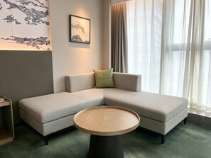 A modern living room with a sectional sofa, a round coffee table, and a framed artwork on the wall.