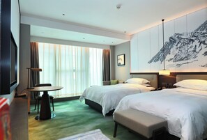 A hotel room with two beds, a desk, a chair, a television, and a large painting on the wall.