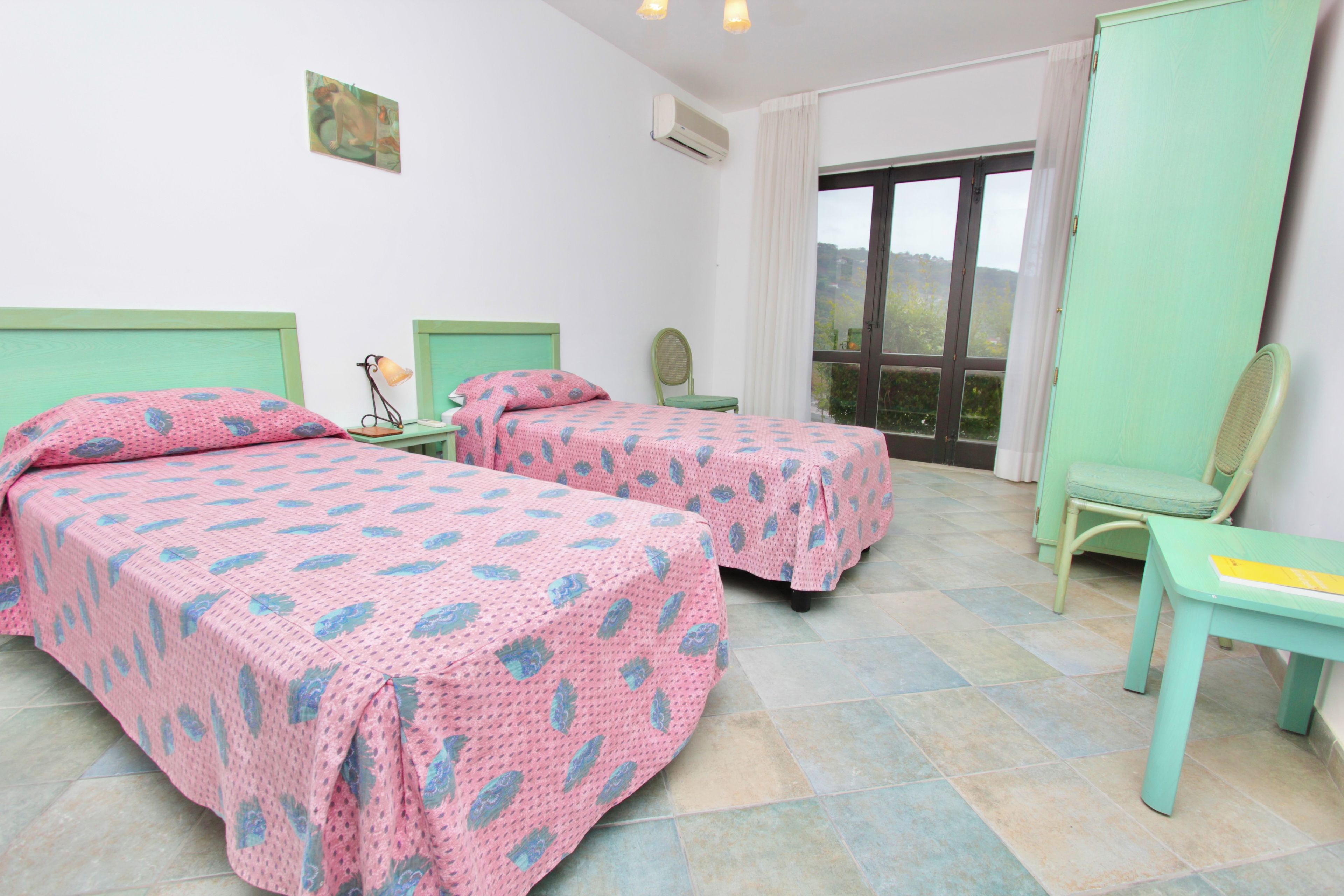 Une chambre avec deux lits, une chaise, un bureau et une fenêtre.