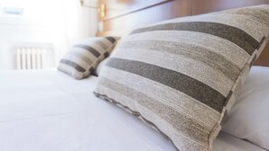 Un letto con cuscini a righe e una testiera in legno.