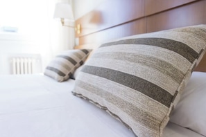 Un lit avec des oreillers à rayures et une tête de lit en bois.