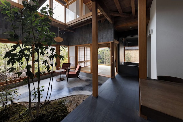 Un intérieur moderne avec un plancher en bois, un coin salon avec des fauteuils et une vue dégagée grâce à de grandes fenêtres.