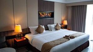 Camera d'albergo con un grande letto, due comodini con lampade, un'opera d'arte appesa alla parete e vista sull'esterno.