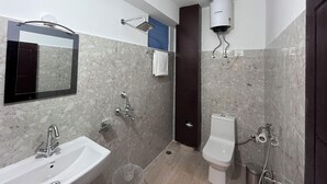 A bathroom with a sink, toilet, shower, and a towel rack. - Ecotel Lachung (Chungthang)