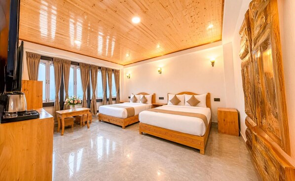 Habitación de hotel con dos camas, un escritorio de madera, una cafetera y un gran panel de madera en la pared.