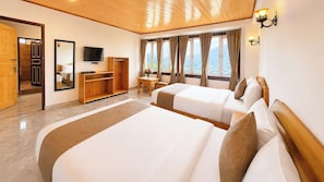 Ein Hotelzimmer mit zwei Betten, einem Fernseher, einem Schreibtisch und Blick auf die Berge.