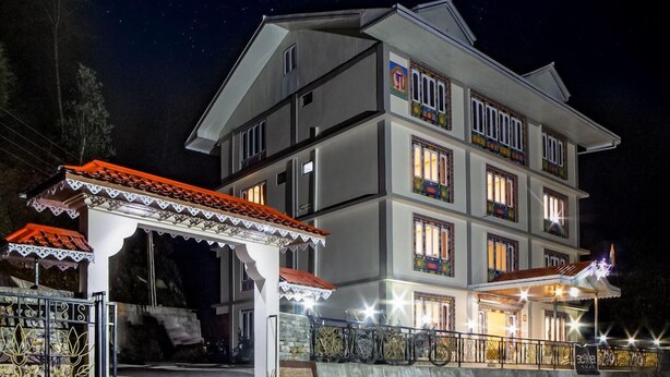 A multi-story building with balconies, a gated entrance, and a covered outdoor area with a tiled roof. - Ecotel Lachung (Chungthang)