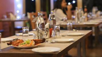 A restaurant setting with tables set for dining, featuring plates of food and various glassware.