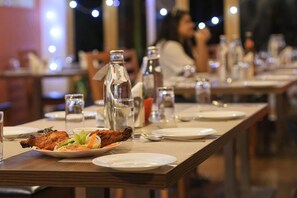 A restaurant setting with tables set for dining, featuring plates of food and various glassware. - Yashshree Karbari Resorts & SPA (Namchi)