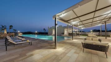 An outdoor pool area with lounge chairs and a covered seating area.