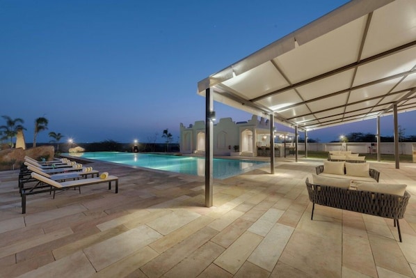 Un espace aménagé au bord de la piscine, avec des chaises longues et un coin salon abrité.