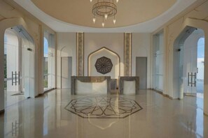 A spacious lobby with a geometric floor design, a reception desk, and a large decorative wall piece. - The Fern Sattva Resort, Little Rann of Kutch (Dasada)