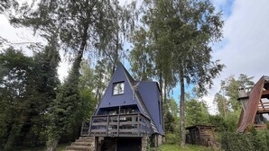 A cabin with a steep roof, a small window, and a stone staircase leading up to the entrance. - Lake Bieszkowice Holiday Cabin (Bieszkowice)