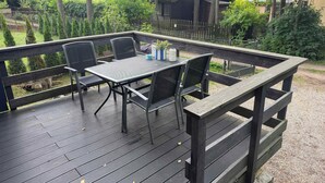 A deck with a table and chairs, surrounded by a wooden fence and trees. - Lake Bieszkowice Holiday Cabin (Bieszkowice)