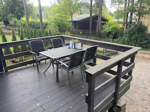 En uteplats med ett bord och stolar, omgiven av ett trästaket och träd.
