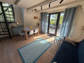 Habitació amb taula de dinar, cadires, un sofà blau, una catifa amb dibuixos i una escala.
