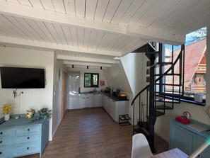 A modern kitchen with a built-in TV, wooden flooring, and a staircase leading to an upper level. - Lake Bieszkowice Holiday Cabin (Bieszkowice)