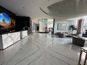 A spacious lobby with a marble floor, a reception desk, seating areas, and a large chandelier. - Hotel Suites - Damac Tower Riyadh (Riyadh)