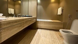 A modern bathroom with a wooden vanity, a toilet, and a large mirror. - Hotel Suites - Damac Tower Riyadh (Riyadh)
