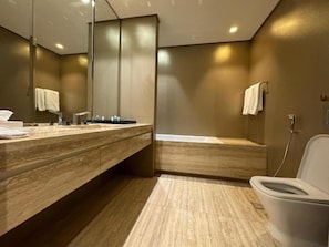 A modern bathroom with a wooden vanity, a toilet, and a large mirror. - Hotel Suites - Damac Tower Riyadh (Riyadh)