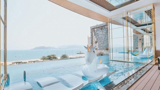 A modern infinity pool with a swan sculpture, clear views of the sea, and a stone wall. - La Vague Hotel (Nha Trang)