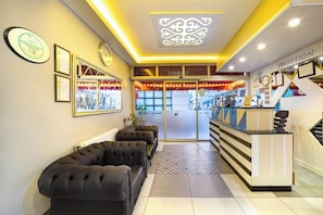 Ein Empfangsbereich mit einer Rezeption, gerahmten Zertifikaten und einer Lounge mit Sofas.