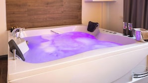 Une salle de bain moderne avec une grande baignoire, un lambris en bois et un meuble blanc placé au-dessus de la baignoire.