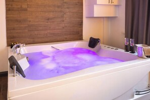 Ein modernes Badezimmer mit einer großen Badewanne, Holzvertäfelung und einem weißen Schrank über der Wanne.