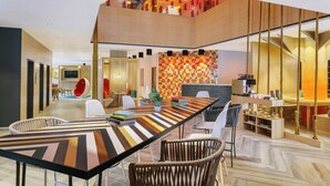 A modern interior with a long dining table, multiple seating options, and a staircase leading to an upper level. - Ginger Nagpur City Centre (Nagpur)