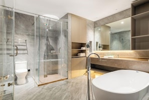Un baño moderno con ducha envuelta en vidrio, bañera independiente y un espejo grande.