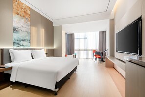 A hotel room with a large bed, a flat-screen TV, a desk with a chair, and a balcony with curtains. - Holiday Inn Express Qidong Economic Zone (Nantong)