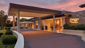 A hotel entrance with a covered walkway, a sign reading "Holiday Inn Express," and a landscaped area with plants and a curved pathway. - Holiday Inn & Suites Batangas Limapark (Malvar)